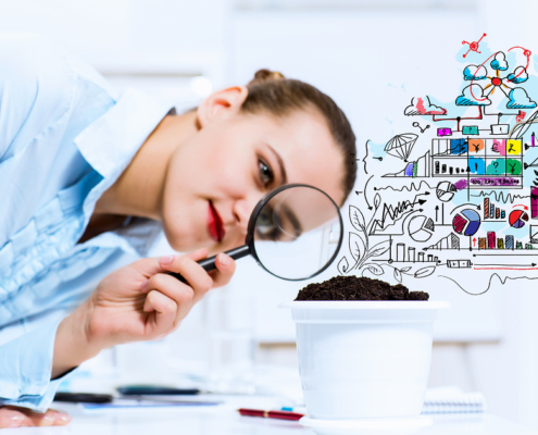 Young businesswoman looking at drawn image of sprout through mag